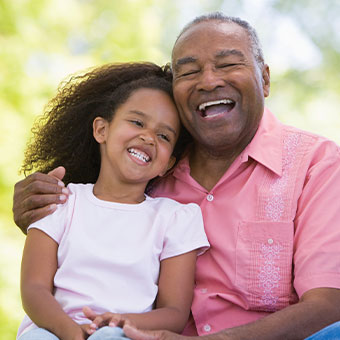 Grandfather laughing with granddaughter. Read about Gifts of Real Estate