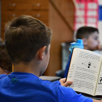 Student sitting down reading a book. Read about Closely Held Business Stock Student sitting down reading a book. Read about Closely Held Business Stock